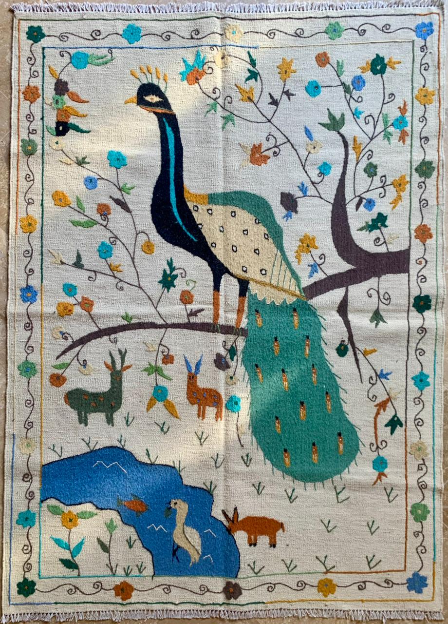 Embroidered fabric with a peacock design surrounded by animals and nature elements.