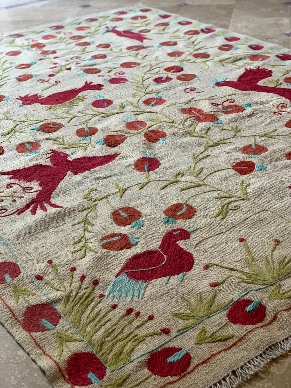 Decorative rug with red bird and floral patterns on a beige background