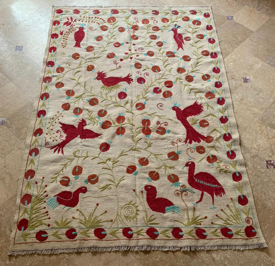 Decorative rug with red bird and floral patterns on a beige background