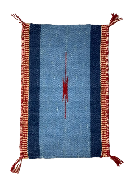 Woven textile with blue center and red abstract design, framed by red border with tassels on a white background